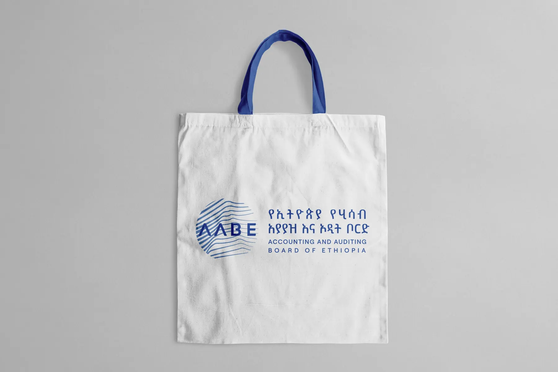 A white seminar tote bag with blue handles and the bilingual AABE logo.
