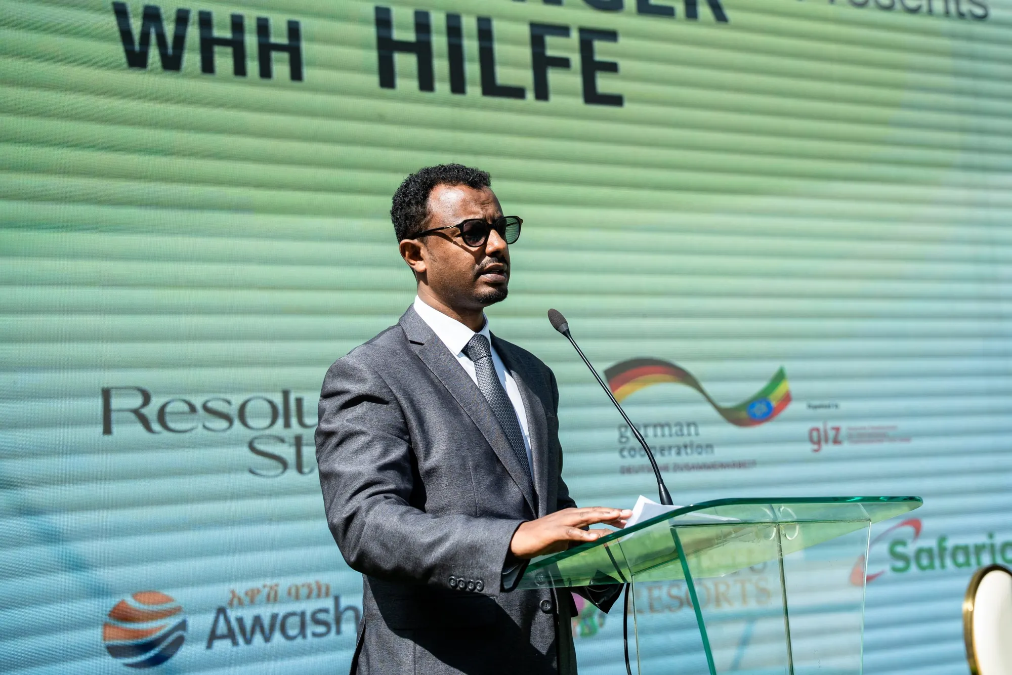 A speaker at the glass lectern in front of the Welthungerhilfe backdrop.