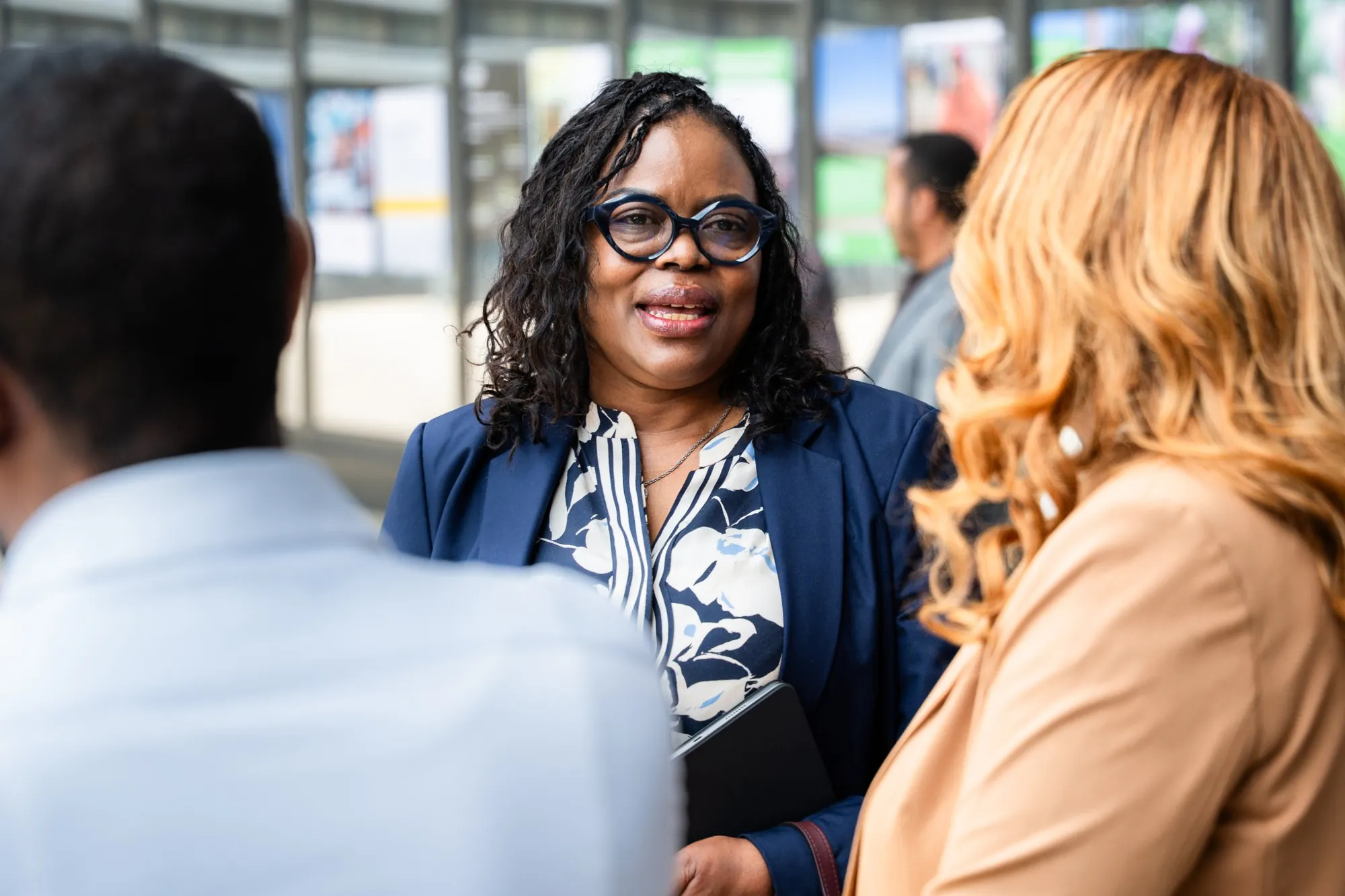 A participant in glasses in conversation during a break, the exhibition behind her.