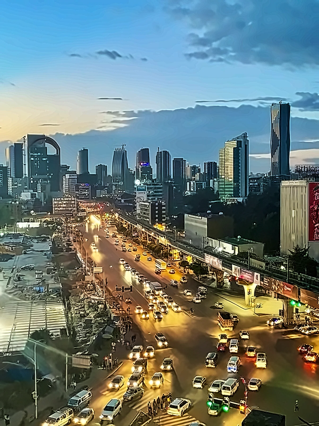 Evening traffic on a wide avenue in Addis Ababa, the skyline lit beyond.