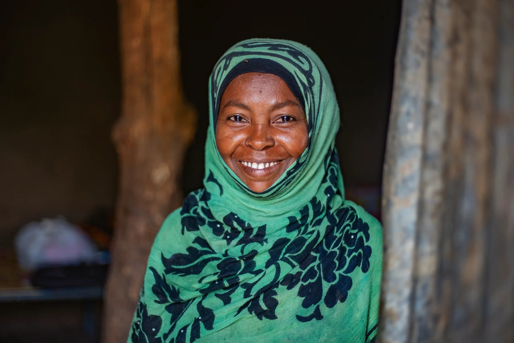 Portrait of a smiling woman in a green patterned headscarf.