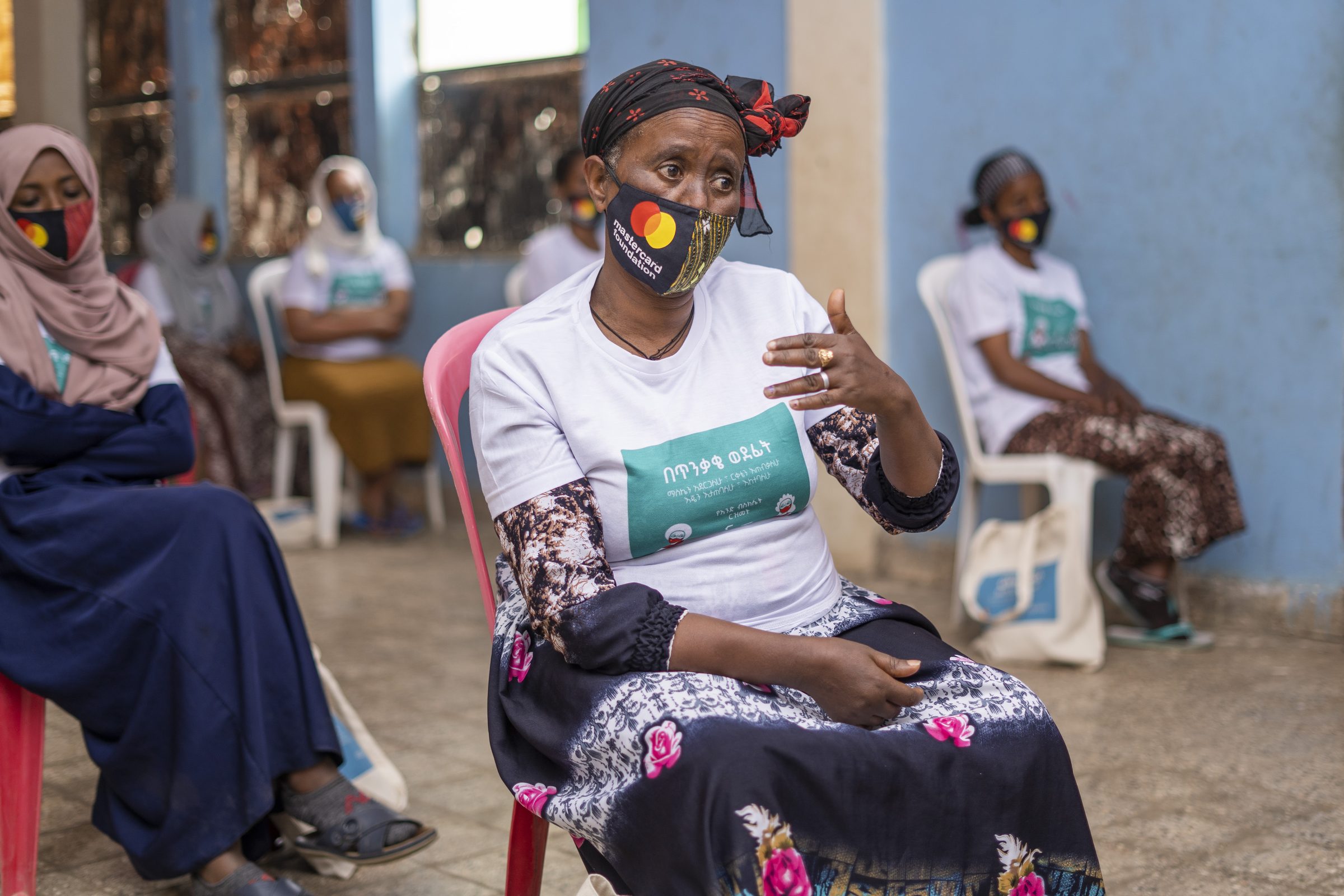 A vendor in a campaign mask speaks during a training session while others listen.