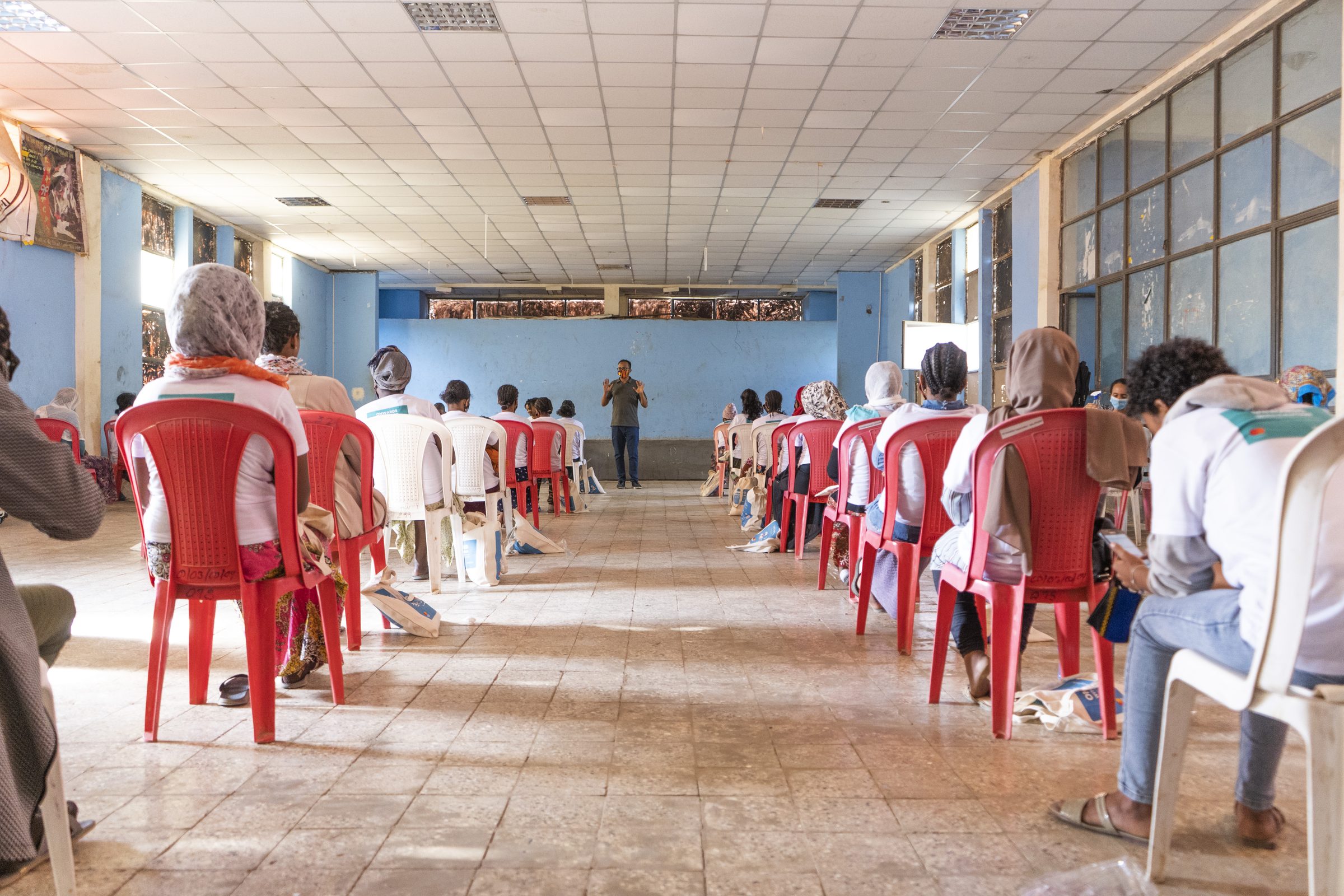 A long hall of coffee vendors seated at a distance from one another during a training session.