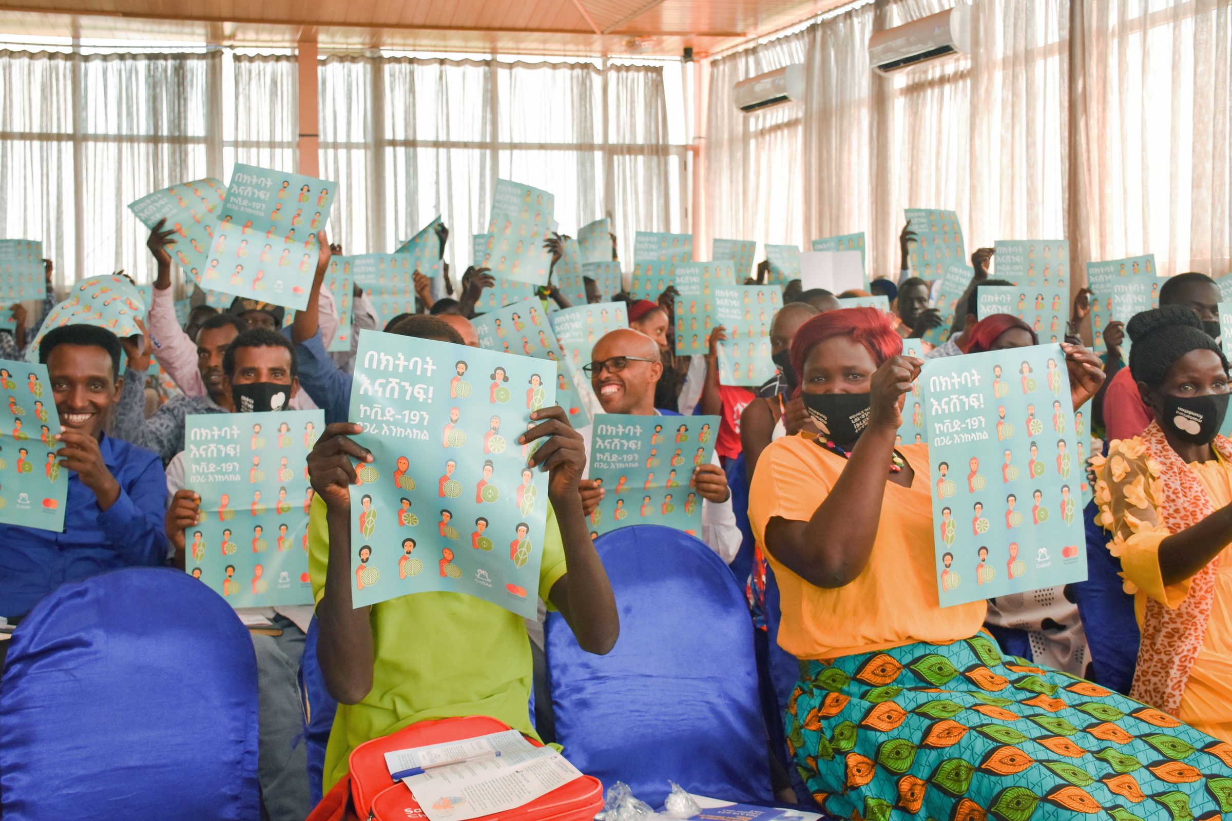Young women seated together hold up campaign flyers.