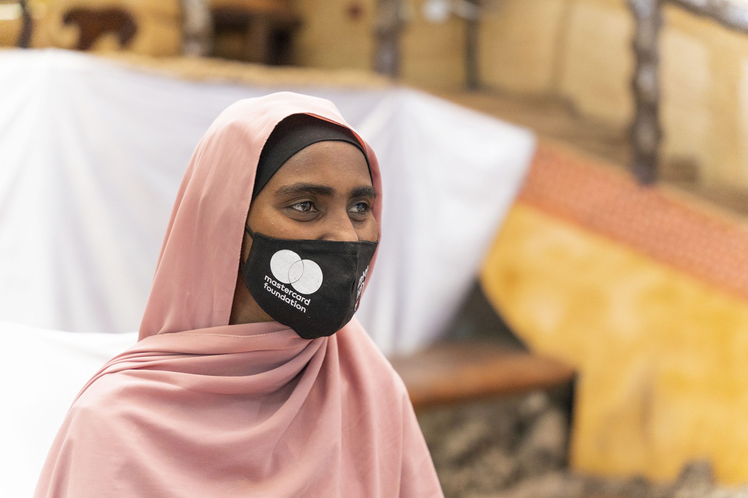 A young woman in a pink headscarf and face mask at a community event in Adama.