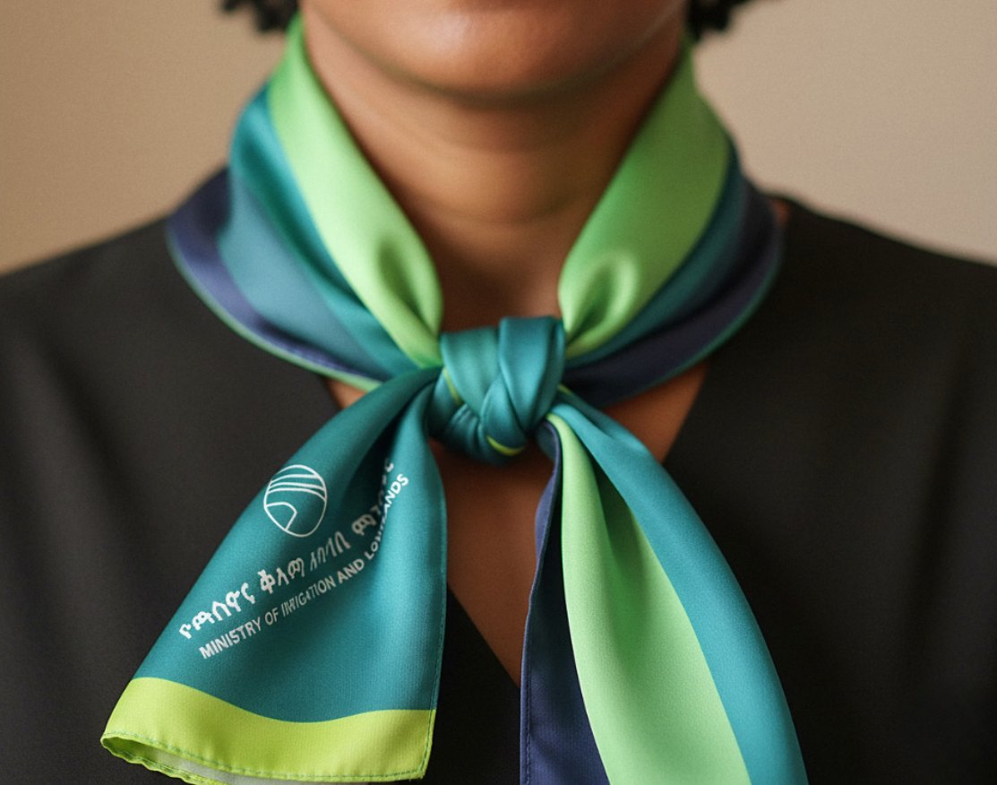 A MiLLS silk scarf worn at the neck, printed with the symbol and the bilingual name.